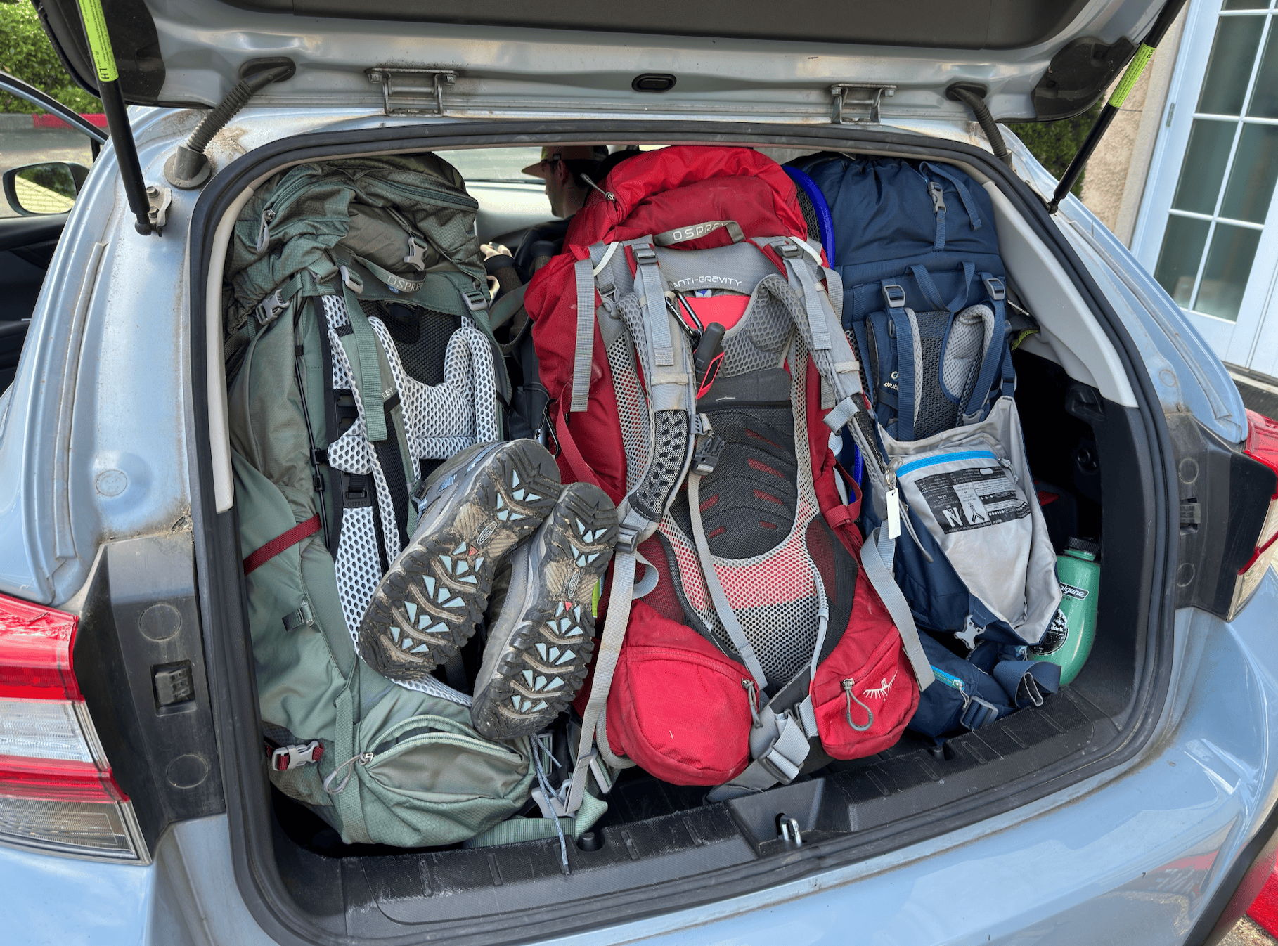 Three backpacks in the back of a car before stepping off onto one of the beautiful trails in the North Cascades in Washington State. These are some of the best women's backpacking backpacks - Gregory and Osprey.